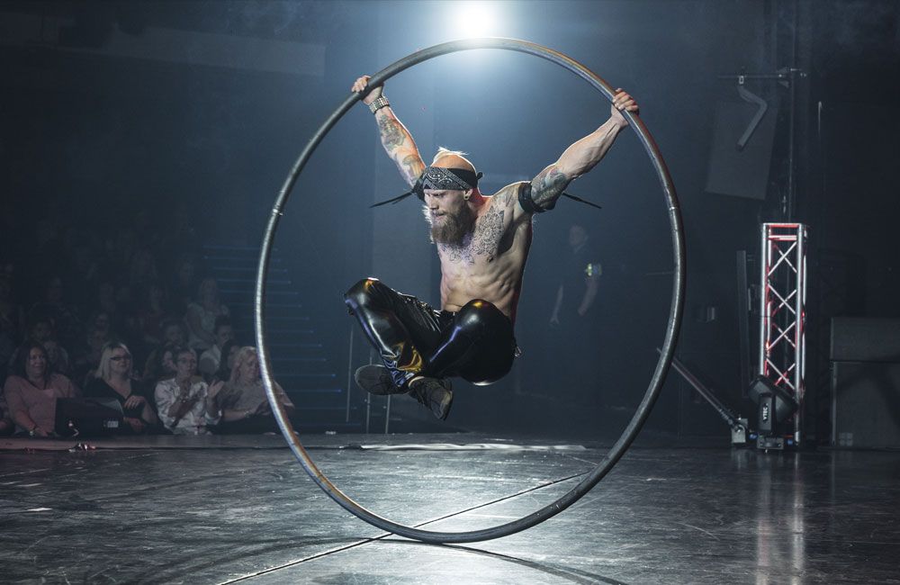 A man performs with a cyr wheel on stage
