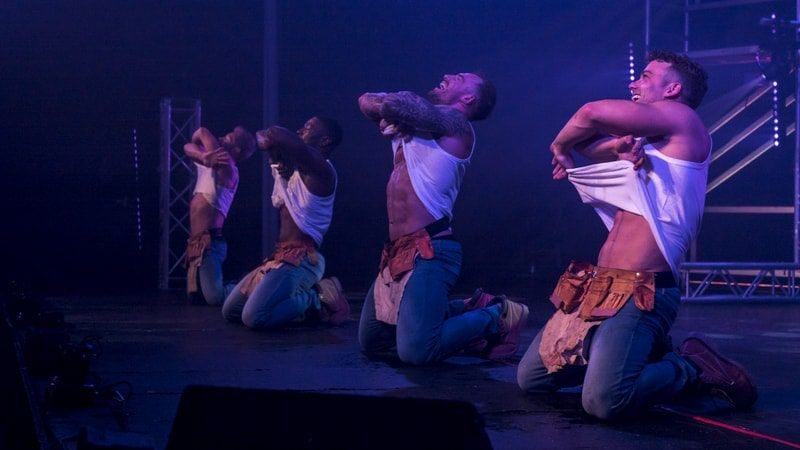 Male strippers remove their tops during a performance on stage